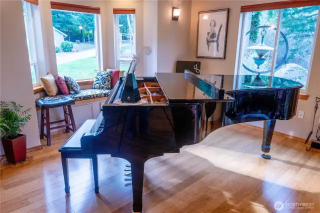 Conservatory portion of the living room with a full size concert piano (can be purchased separately).  The bay window seat is a perfect place to retreat to while relaxing to the music.  The natural beauty of the bamboo floors really shines against the lines of the piano.
