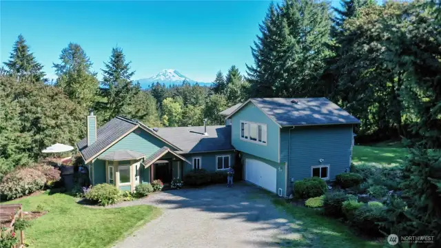 Elegant front door entry with stained glass side windows. Entrance to the home is from the West.  Mt Rainier is in the background.  Home has a finished attached double car garage and a separate detached two car garage/shop not shown in this photo.
