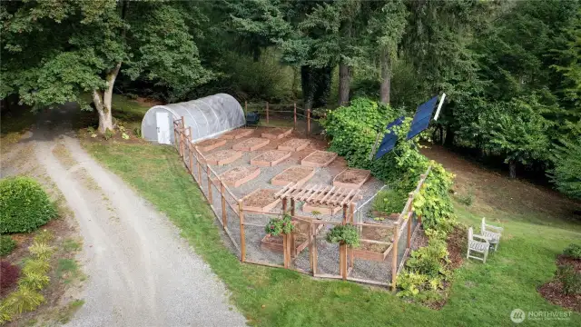 Fenced garden with sixteen raised beds & green house. Not visible but on the property are two in-ground water storage tanks, two below ground owned propane tanks and one above ground propane tank. Solar panels on the roof of the home and a 6KW generator system.