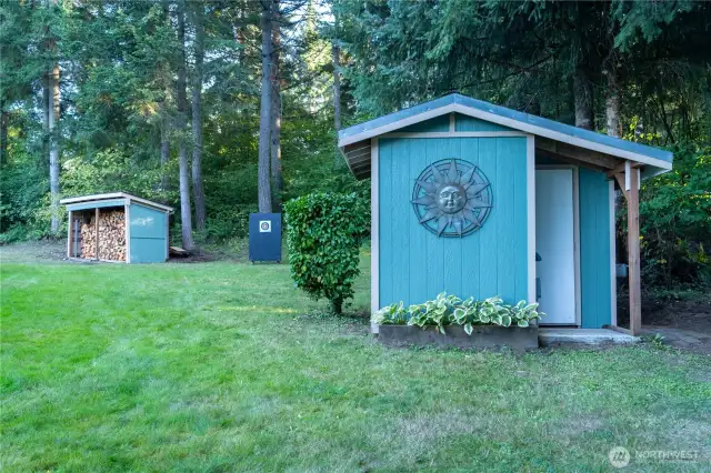 Well house with two electric submersible pumps (240V and 110V), with hand pump. Wood shed in the background holds 4 cords of firewood. All outbuildings freshly painted to match the main home. Additional 1.5KW Onan propane generator housed inside to run water system during power outages.