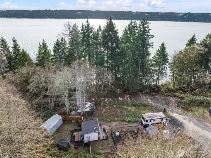 Aerial view showing the full 1-acre hillside layout with multiple leveled areas, established driveway access, cleared pads, and forested surroundings. Property backs directly to DNR land for added privacy.