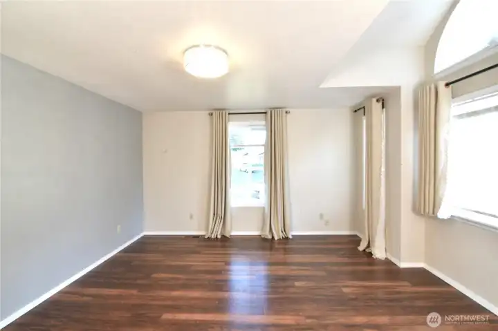 light-filled primary bedroom with large windows and decorative half-moon window