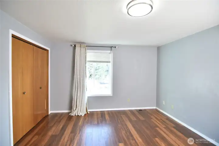 first bedroom with hardwood floor overlooking backyard