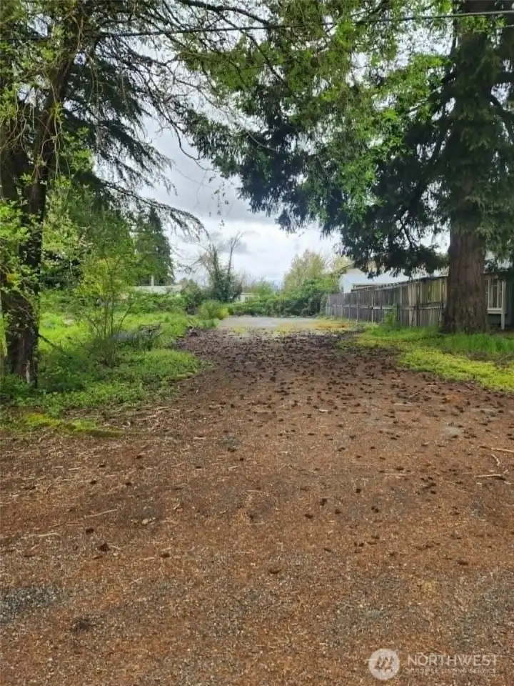 Entrance to vacant lot, partially fenced, mature trees