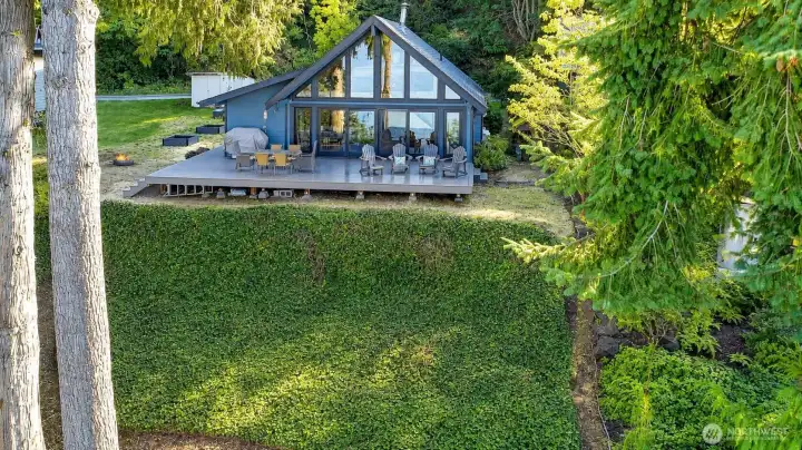 Waterfront home on Puget Sound featuring private beach access, outdoor fire pit, and serene views surrounded by evergreens.