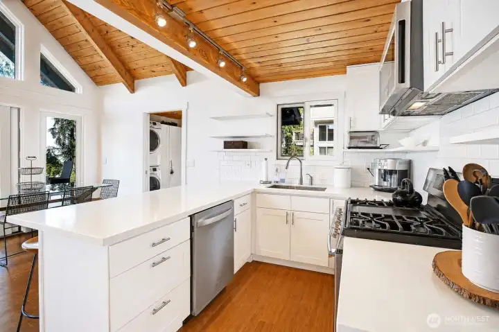 Completely renovated kitchen featuring new cabinets, all new appliances including microwave hood and dishwasher, quartz countertops, and floating shelving for a modern, functional space.