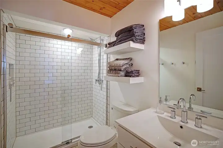 Fully renovated bathroom with new shower, stone tile flooring over radiant heating, modern fixtures, updated doors and trim.