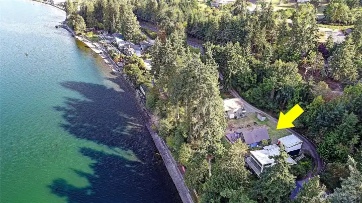 Waterfront home on Puget Sound featuring private beach access, outdoor fire pit, and serene views surrounded by evergreens.