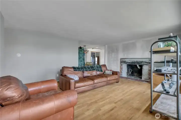 living room features original hardwood floors and a cozy gas fireplace, creating a warm and inviting central gathering space.
