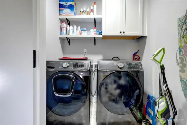 Separate laundry room with shelves and cupboard space above.