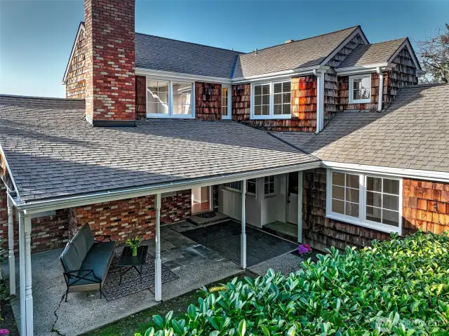 Sheltered beneath the eaves and framed by manicured hedges, this covered entry whispers welcome with every sea breeze. Shingled in timeworn cedar and anchored by twin chimneys, the home’s classic Cape Cod silhouette sets a graceful tone—inviting you into a life perched above Caledonia Cove, where every arrival feels like a return.
