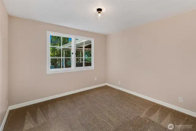 Freshly carpeted and full of natural light, this quiet bedroom offers a peaceful retreat overlooking mature greenery. Whether used for guests, a home office, or creative studio, it reflects the home's overall charm—simple, serene, and ready to adapt to your needs on the hillside above Caledonia Cove.