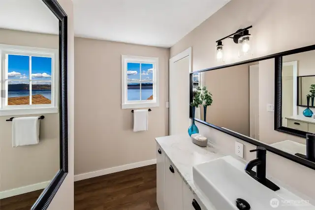 Clean lines, matte black fixtures, and a sleek vessel sink bring contemporary style to this refreshed bath—while the window offers a surprising delight: a view of Puget Sound stretching to the horizon. It’s a space that balances function with beauty, reflecting the thoughtful updates woven throughout this Browns Point Cape Cod.