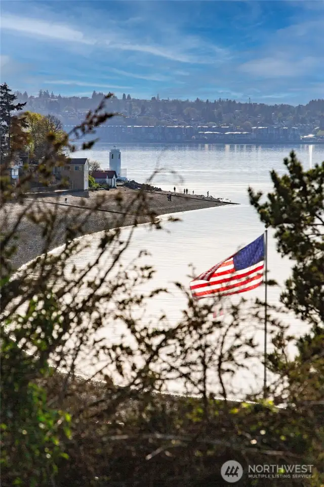 From your upland perch above Caledonia Cove, this is the scene that greets you—an American flag catching the sea breeze, the lighthouse standing watch, and the tide tracing its path along the curve of Browns Point. It’s a living landscape, where every hour brings a new expression of sky, water, and wonder.