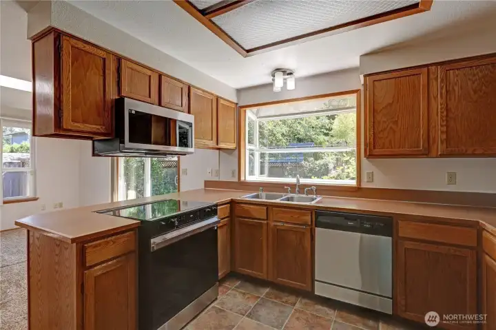 Bright kitchen with abundant cabinet storage, stainless steel appliances, and a large window overlooking the backyard.
