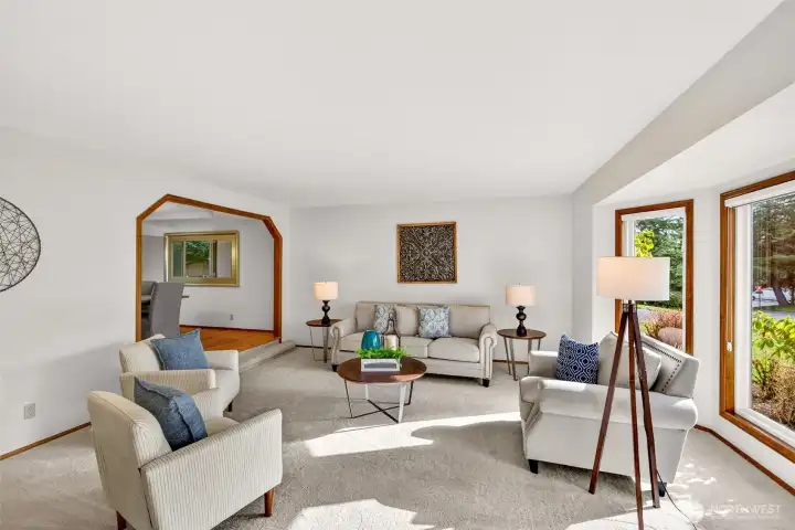 An expansive living room with generous wall space for art and media, plus a large window that brings in natural light. The layout offers flexible options for gathering, relaxing, or creating a quiet reading area.