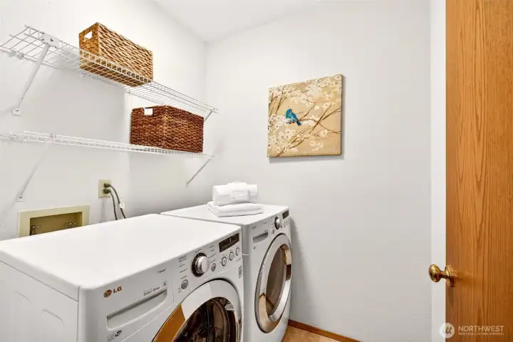 Dedicated laundry room with built in shelving for organization and supplies, plus space for full size machines. A practical utility space that keeps day to day tasks tucked away and tidy.