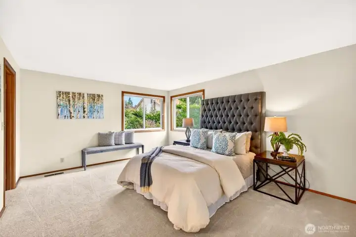 Primary bedroom retreat with soft carpeting, corner windows for natural light, and ample space for a king size layout plus additional flexibility. A calm, comfortable setting to start and end the day.