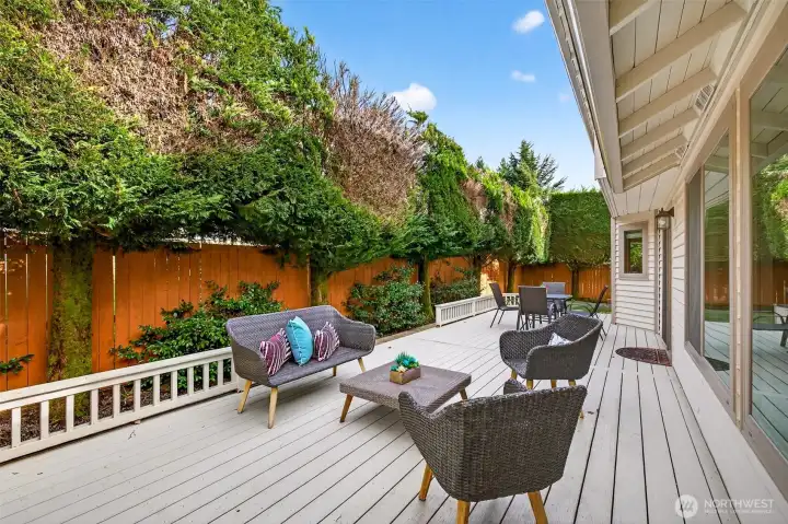 Private deck designed for outdoor lounging and dining, framed by mature evergreens and fencing for a tucked away feel. An easy extension of the main level living space for grilling, relaxing, and entertaining.