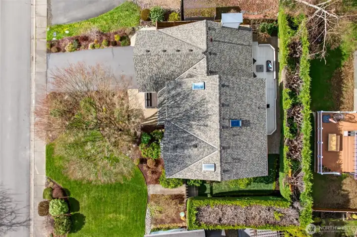 An arial view of the home highlights the home’s two story footprint and the practical outdoor layout, including deck, patio, and lawn area. A great balance of hardscape and greenspace for daily enjoyment.