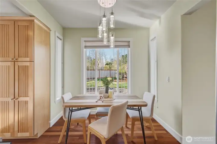 Charming breakfast nook with beautiful lighting and a picture window peering out the private backyard retreat. A pantry or extra storage cabinet is also pictured here.