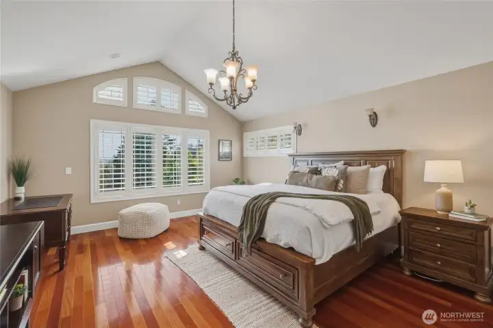 Spacious primary suite with vaulted ceilings, mahogany wood floors, and large windows to capture the beautiful views.