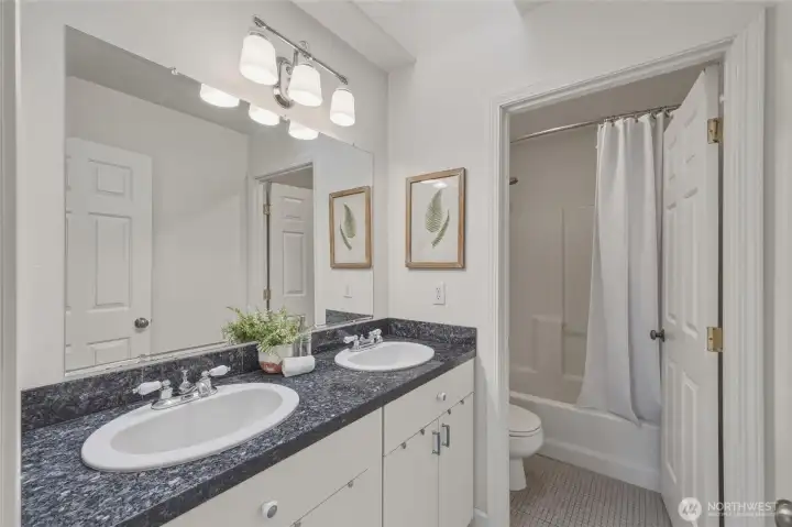 In between the guest bedrooms is another full bathroom with double sinks and a bath/shower combo.