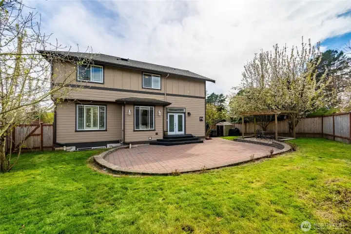 Fully fenced backyard with huge patio for entertaining, a storage shed, a gazebo, fruit trees, rose bushes and a garden bed.