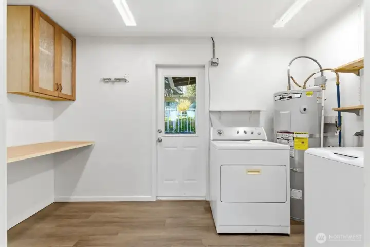Large laundry room with folding table, storage & door to outside.