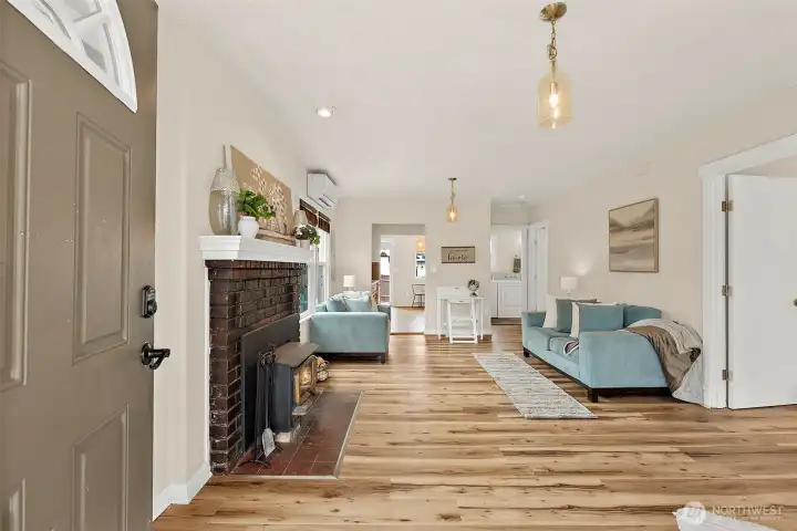Bright and inviting living room featuring updated flooring, abundant natural light, and a cozy wood stove fireplace centerpiece.