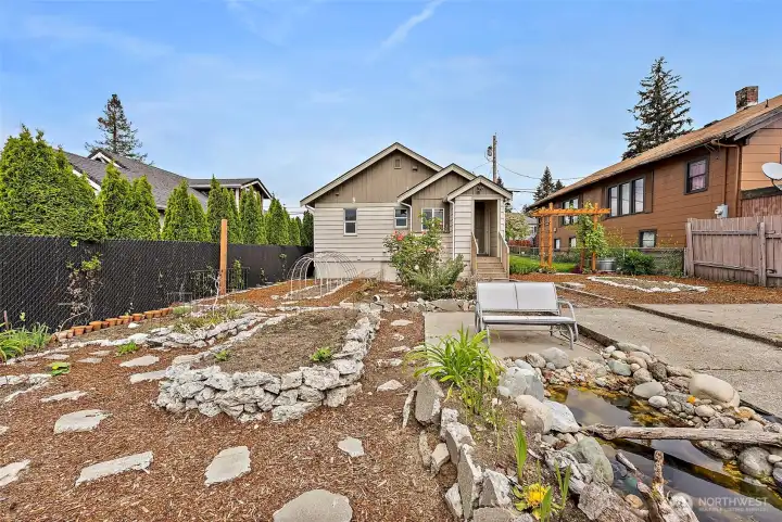 Expansive backyard retreat features mature landscaping, raised garden areas, and versatile outdoor living potential.
