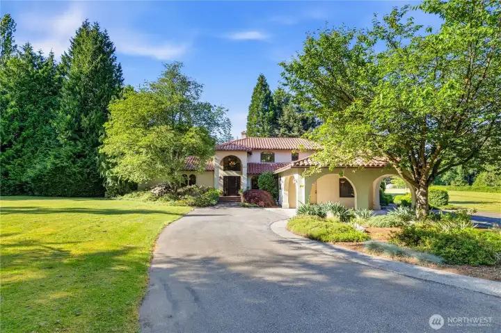 Lush landscaping including beautiful flowering trees and round about driveway.