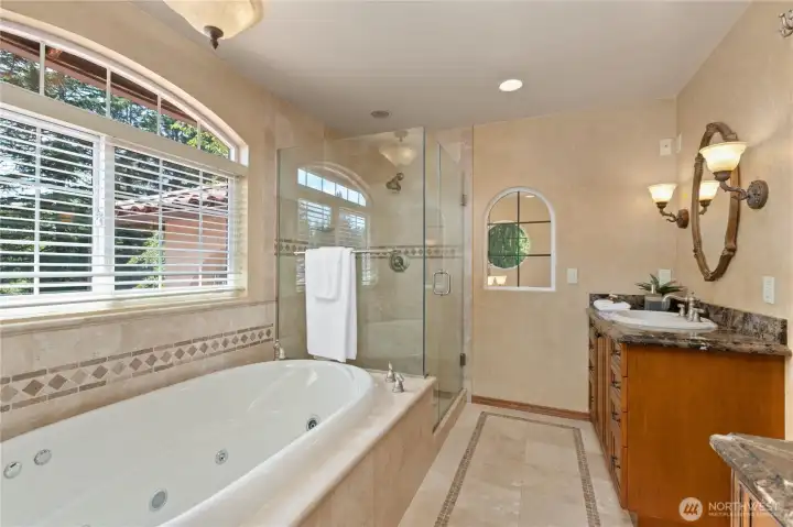 Beauitful primary en suite bathroom with two vanities, standing walk-in glass shower and jetted Whirlpool tub.