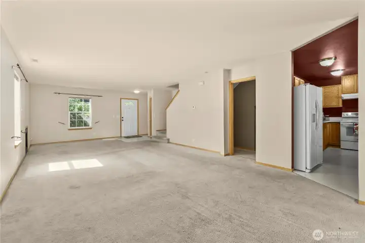 Wider view of the living room from the dining area, showing the kitchen on the far right and the half bath next to it.