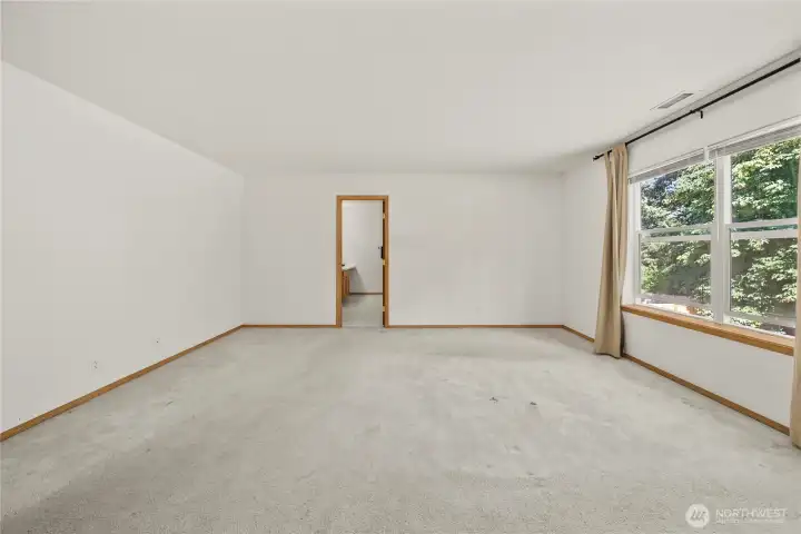 Primary suite includes this HUGE bedroom w/ large window to let the natural light in. Straight ahead is the doorway to the Private Bathroom.