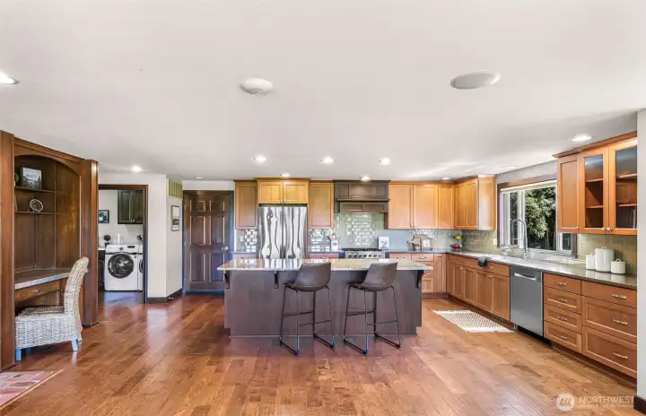Spacious kitchen, with newer stainless appliances, corian counters, wood floors, desk area and easy access to laundry area and built in desk.