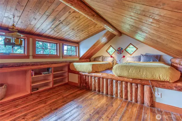 A custom madrona wood staircase leads to a spacious loft sleeping area, complete with built-in storage drawers and shelving.