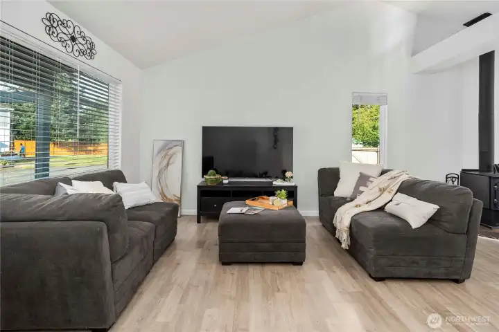 Vaulted ceilings and a cozy wood-burning stove create a warm, open atmosphere