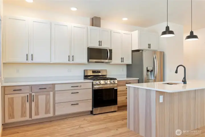 Lovely contrast of lower hickory cabinets with white maple uppers. Sparkling quartz countertops complete with gas range, all brand new appliances.