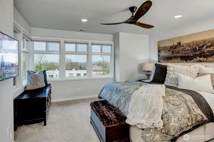 Primary bedroom with wall of windows and Restoration Hardware fan.