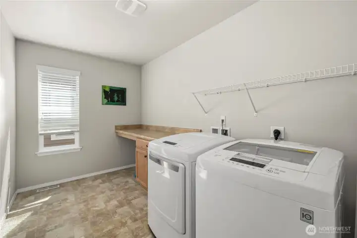Upstairs laundry room featuring a convenient folding area and additional storage