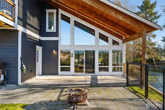 Patio area in back of house for outdoor entertaining, leading to the fully fenced yard and dock