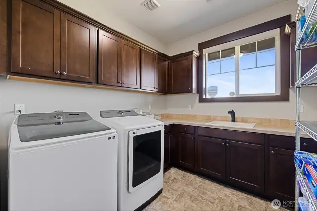 Large laundry room with sink, generous countertop space, and ample cabinetry. Bonus area for additional storage.