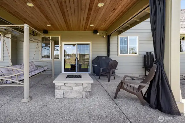 Covered patio includes a built-in propane fireplace and protective shades for comfort and bug-free evenings.