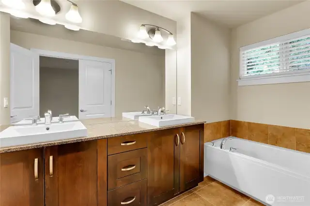 A second set of double doors leads into the luxurious five-piece primary bath which is also very spacious.  16 x 16” tile flooring runs throughout the primary bath, making it look luxurious and making it easy to clean.  The extra-tall vanity is topped with a long granite countertop with two rectangular raised sinks.