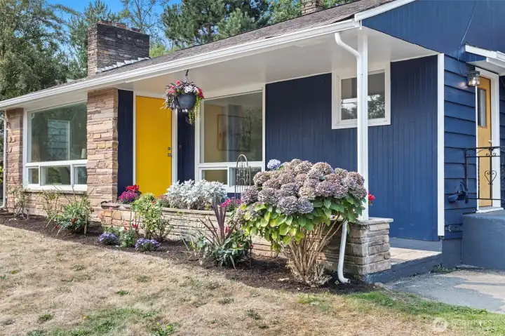Hydrangeas, stone-faced planter beds, and layered textures brighten the entry path.