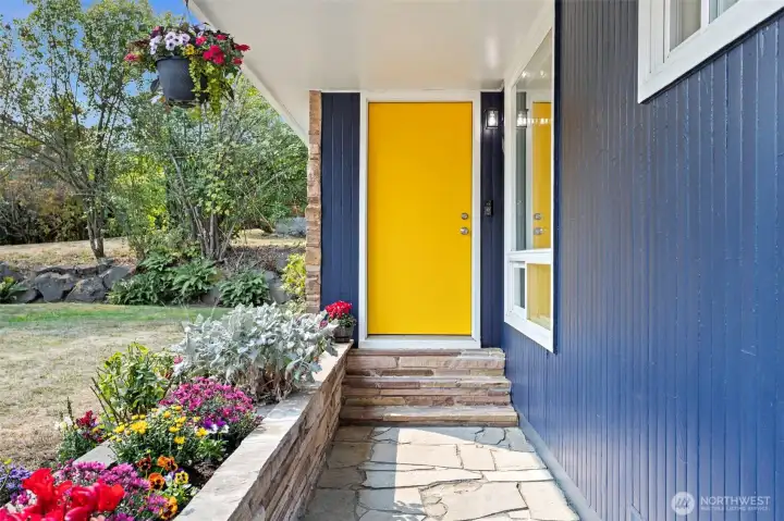 Covered flagstone walkway with classic sandstone and cheerful blooms—an inviting approach that sets the tone for home.