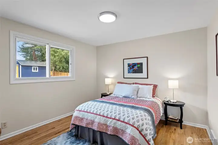 North bedroom overlooks the backyard with a wide western view—sunlight all afternoon and newly refinished oak floors underfoot.
