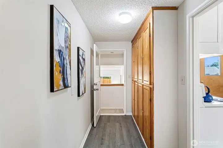 This second hallway connects the kitchen to the lower-level flex space and adds serious function with a full wall of oak cabinets, a second coat closet, and matching LVP flooring.