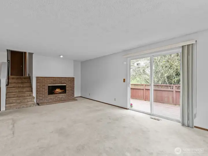 As the top of the stairs is another large living room with fireplace and access to the elevated deck. The stairs are enclosed with a gate.